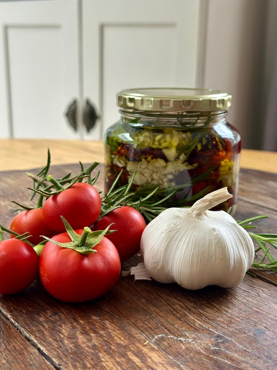 Woodenboard with fresh garlic and tomatoes and a bottle of preserves